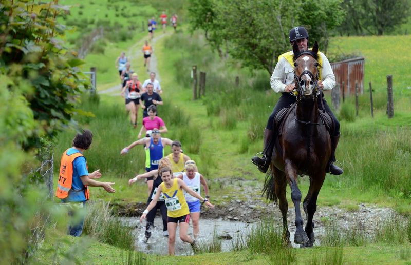 LLANWRTYD WELLS, WALES - JUNE 14: In this handout image provided by Whole Earth Peanut Butter, runners and riders compete in the Man v Horse Marathon powered by Whole Earth Peanut Butter on June 14, 2014 in Llanwrtyd Wells, Wales. The annual race, which started in 1982 sees runners compete against riders on horse-back over 24 miles of challenging terrain. (Photo by Whole Earth Peanut Butter via Getty Images)